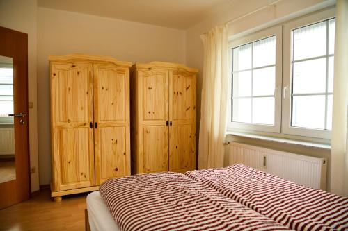巴特贝勒堡Ferienwohnung am Rothaarsteig的一间卧室配有一张带木制橱柜的床和窗户。
