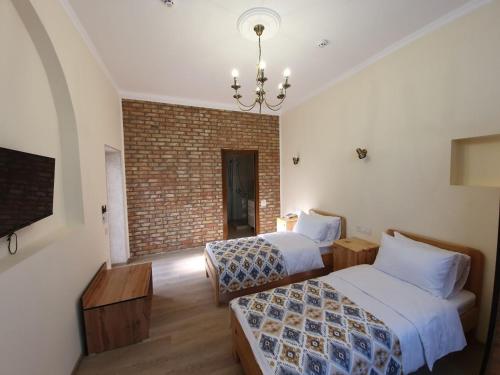 塔什干Chorsu Inn的一间卧室设有两张床和砖墙