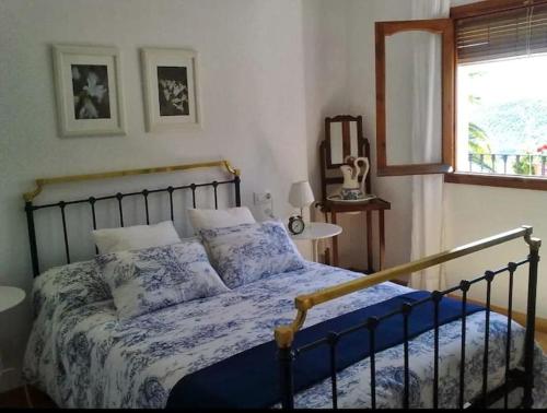 伊斯纳哈尔La Villa, Alojamiento Rural的一间卧室配有一张带蓝色床单的床和一扇窗户。