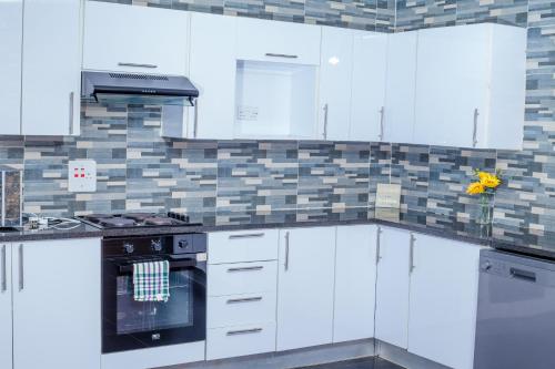 卢萨卡Carsi holiday Villa的厨房配有白色橱柜和炉灶烤箱。