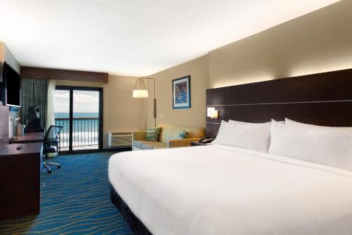 代托纳海滩Holiday Inn Express & Suites Oceanfront Daytona Beach Shores, an IHG Hotel的酒店客房设有一张大床和一个阳台。
