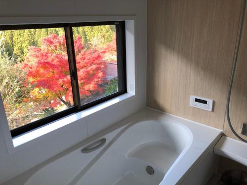 三好市卡租拉亚旅馆的带窗户的浴室内的白色浴缸