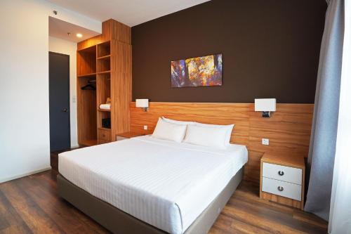 怡保Sunway Onsen Hospitality Suites的卧室配有白色的床和木制床头板