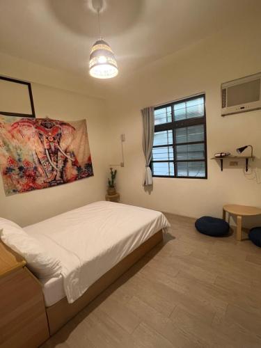 小琉球岛暖流背包客栈的卧室配有一张床,墙上挂有绘画作品