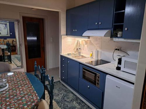 卡兰巴卡Kalian Meteora的厨房配有蓝色橱柜、水槽和桌子