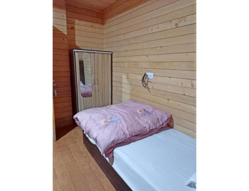 佩林Cherry Village Resort, Pelling, Sikkim的木墙客房内的小床