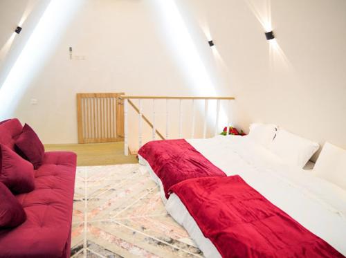 SharīyahRed_Hut_Resort的一间卧室配有一张大床和一张红色的沙发