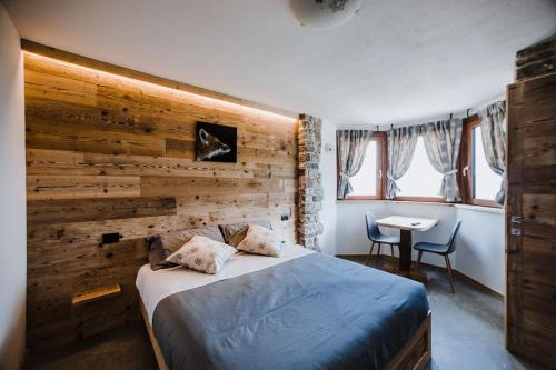 Zambla AltaAtelier della Montagna的一间卧室设有木墙、一张床和一张桌子