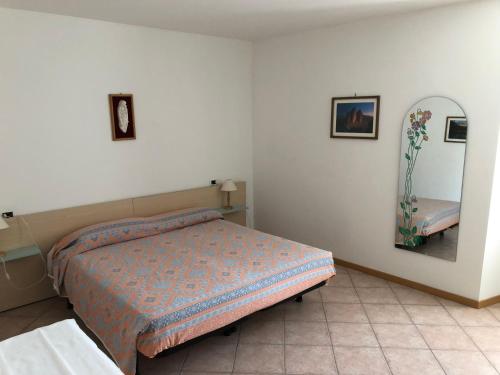科雷多Appartamento Rosa的卧室配有一张床,墙上设有镜子