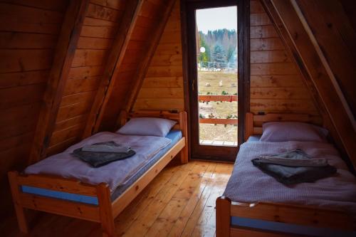 帕莱Vikendica Tromedja Pale的小木屋内的两张床,设有窗户