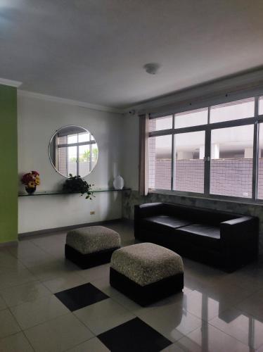 圣维森特岛Lindo apto vista lateral do mar Itararé São Vicente的客厅配有黑色沙发和镜子