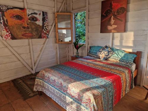 Santo AntónioWorld's View Wild Camping Salaszoi, Principe Island的卧室配有一张床,墙上挂有绘画作品