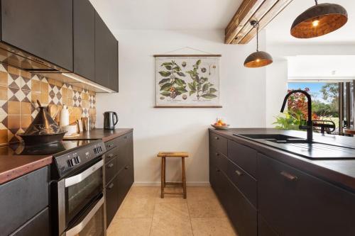 拜伦湾Byron Pacific Apartments - On Clarkes Beach的厨房配有黑色橱柜和水槽