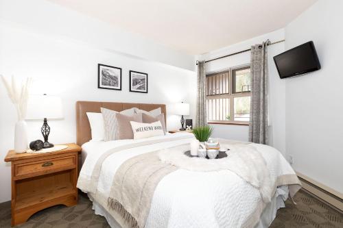 惠斯勒Slopeside Whistler Creek的白色的卧室设有一张大床和一个窗户