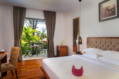 暹粒库伦酒店的一间卧室配有一张床、一张书桌和一个窗户。