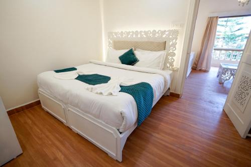 坎多林Lillywoods Highland Beach Resort- Candolim的卧室配有带蓝色枕头的大型白色床