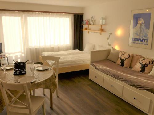 采尔马特采尔马特精品酒店的小房间设有床和桌子以及用餐室