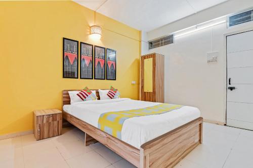 浦那OYO Home Saraswati Niwas Vadgaon Budruk Near Fun Time Multiplex的一间卧室设有一张大床和黄色的墙壁