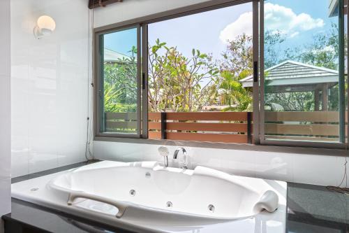 查龙Villa Piyada的带窗户的浴室内的白色浴缸