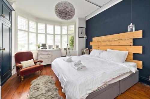 伦敦Stunning one bedroom flat with large terrace in Chiswick by UnderTheDoormat的一间卧室设有一张蓝色墙壁的大床