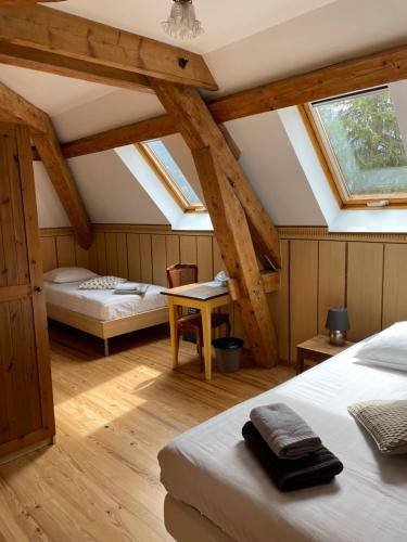 Saint-Pierre-dʼEntremontl'Ancienne Ecole du Villard的阁楼卧室配有两张床和一张桌子