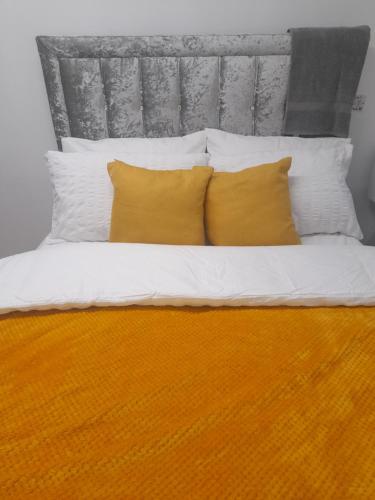 卢顿1 bed studio的一张带两个黄色枕头和床头板的床