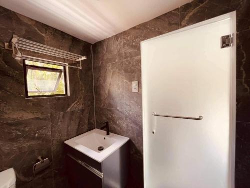 TayabasA House Lucban Resort & Spa的浴室设有白色门和水槽