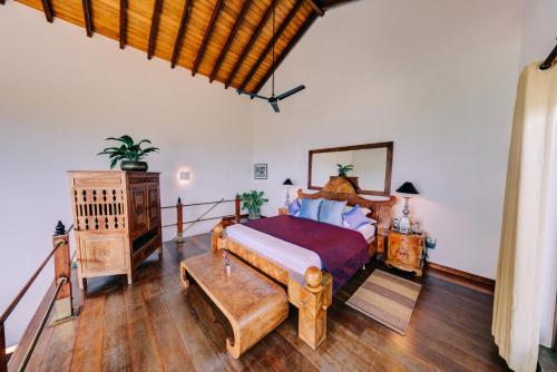 希克杜沃Aditya Resort的一间卧室设有一张大床,铺有木地板。