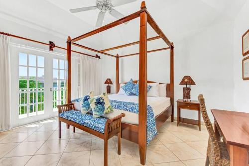 圣彼得教区Blue Horizon Battaleys Mews lovely secure villa 5 minutes from Mullins beach的一间卧室配有一张天蓬床、椅子和一张桌子