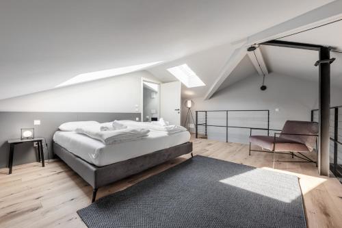 博尔扎诺Stay COOPER l CITY LOFT的白色卧室配有一张大床和椅子