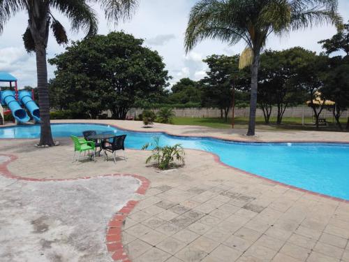 Kitwe莫巴酒店及会议中心的游乐场旁带桌椅的游泳池