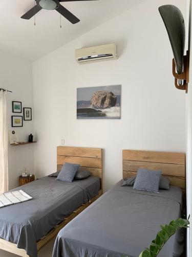 圣塔特蕾莎海滩El Chante Surf House的白色墙壁客房的两张床