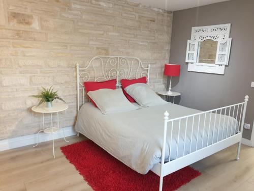 桑利斯Le Gîte Senlisien的卧室配有带红色枕头的白色床