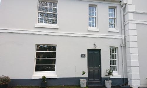 托基Lincombe Court Apartment Wellswood Torquay的一间白色的房子,有黑色的门和两盆植物