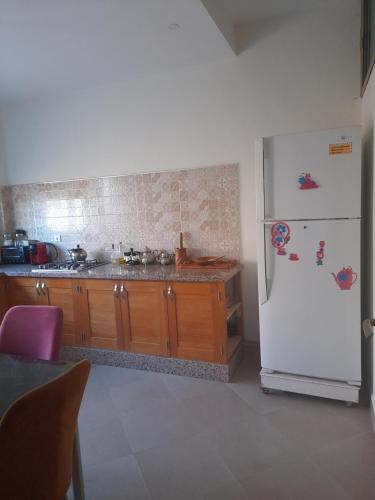 海尼夫拉Appartement ennasr49的厨房配有白色冰箱和木制橱柜。