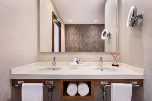 圣朱利安斯马耳他圣朱利安斯丽笙度假酒店的浴室设有2个水槽、镜子和毛巾。