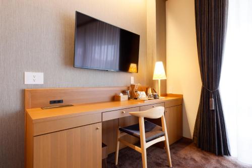 樱井市Hotel Nara Sakurai No Sato的一张桌子,位于酒店的房间,配有椅子和电视