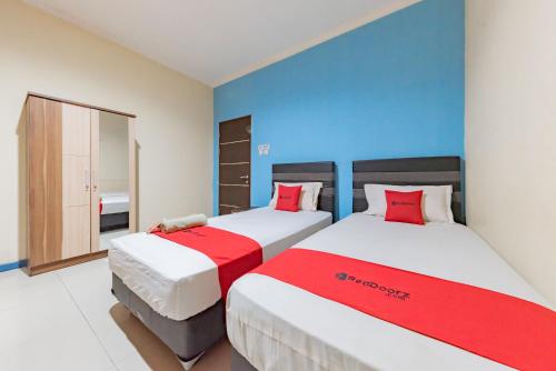 沙马林达RedDoorz Syariah @ Pangeran Suryanata Samarinda的一间卧室配有两张红色和白色床单