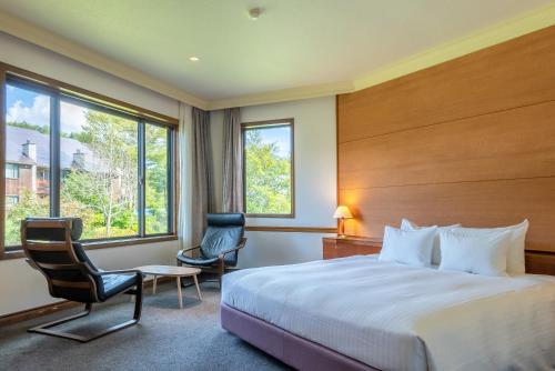 白马村白馬塞拉度假酒店的酒店客房,配有一张床和两把椅子