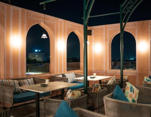 斋浦尔Bur'Dera - a Boutique Luxury Hotel的一间晚上设有桌椅和窗户的餐厅