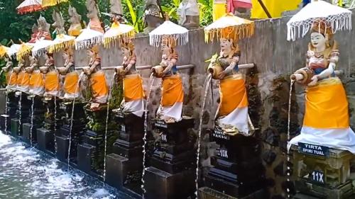 SusutPenglukatan Dasa Mala Lan Tirta Widiadari的一群佛像在水边的墙上