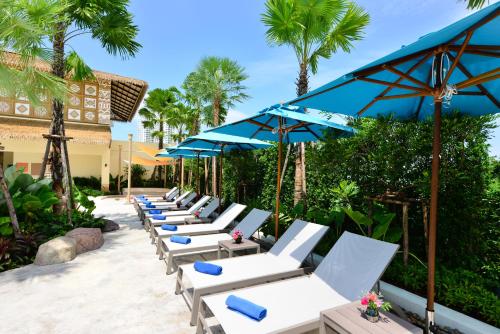 北芭堤雅Centre Point Prime Hotel Pattaya的庭院里摆放着一排躺椅和遮阳伞