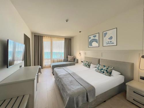 金沙GRIFID Moko Beach - 24 Hours Ultra All Inclusive & Private Beach的一间卧室配有一张大床和一张沙发
