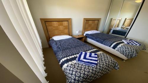 朱里恩湾Unit 64 Seafront Estate的一间设有两张蓝色和白色毯子的床的房间