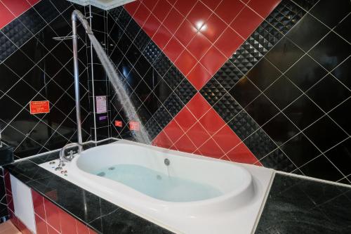 台南夏阁精品汽车旅馆 的浴室设有浴缸,铺有红色和黑色瓷砖。