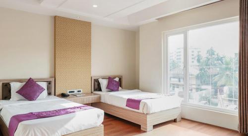 古瓦哈提HOTEL THE KALYANIZ的一间卧室设有两张床和大窗户