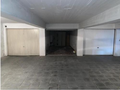 克诺克－海斯特Knokke Modern Studio的一间空房间,设有两个车库门,铺有瓷砖地板
