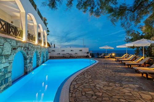 阿梅尼斯蒂斯埃罗费里海滩酒店的一座带椅子和遮阳伞的游泳池位于一座建筑旁边