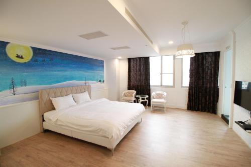 台南Key We Go Hotel 奇遇果文旅的卧室配有一张床,墙上挂有绘画作品