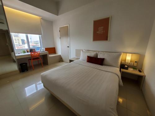 雅加达竺立快递芒甘杜阿旅馆的酒店客房设有一张白色大床和一张书桌